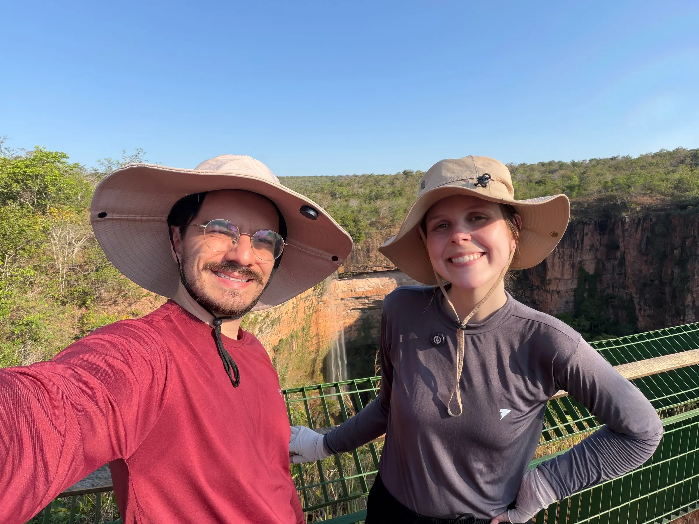 Lucas e Gabriella, de chapéu, sorrindo num mirante com o cânion e a mata ao fundo