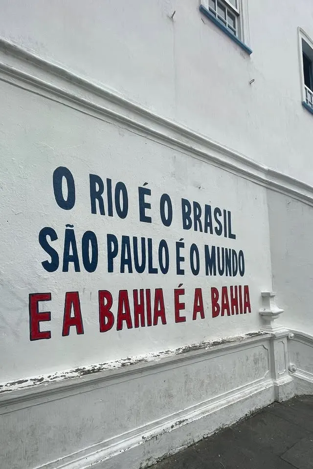 Parede branca pintada com a frase: O Rio é o Brasil, São Paulo é o mundo e a Bahia é a Bahia